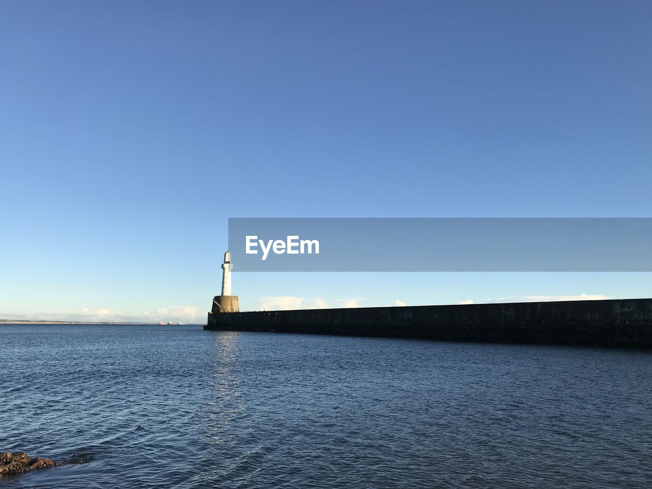 LIGHTHOUSE ON SEA AGAINST CLEAR BLUE SKY