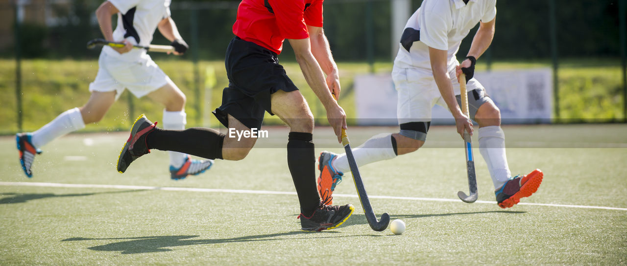 Low section of men playing hockey on turf