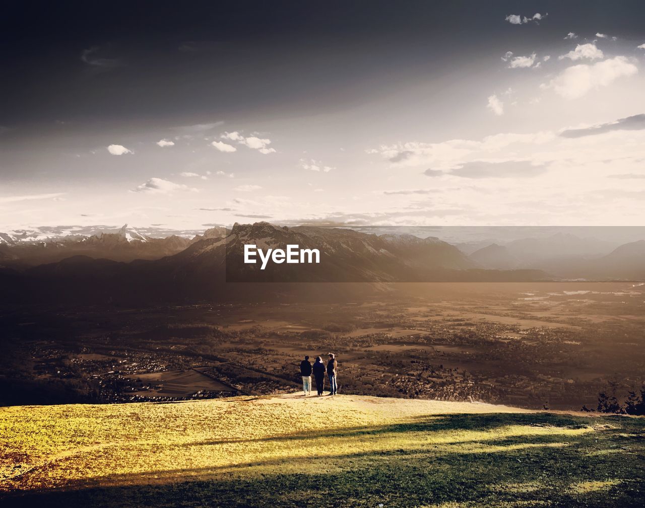 REAR VIEW OF FRIENDS STANDING ON FIELD AGAINST SKY DURING SUNSET