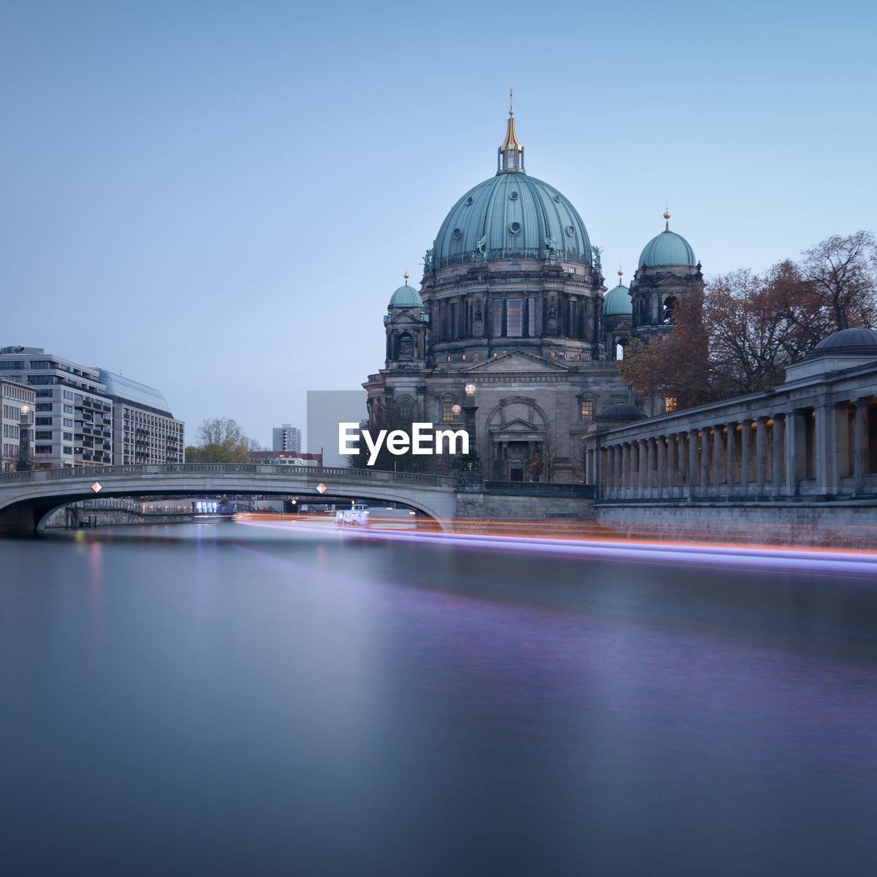 Light trail over river by berlin cathedral against clear sky at dusk