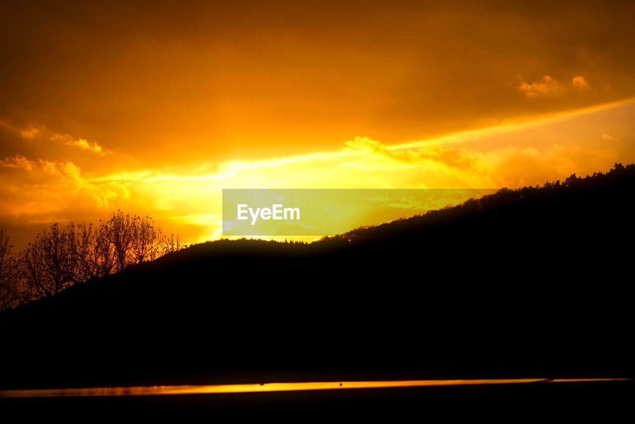 SCENIC VIEW OF SILHOUETTE MOUNTAIN AGAINST ORANGE SKY