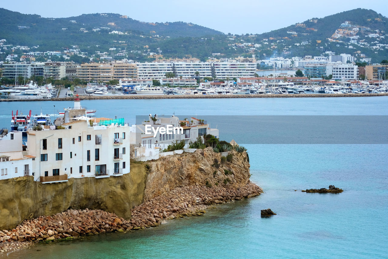 Panoramic view of sea and townscape against mountain