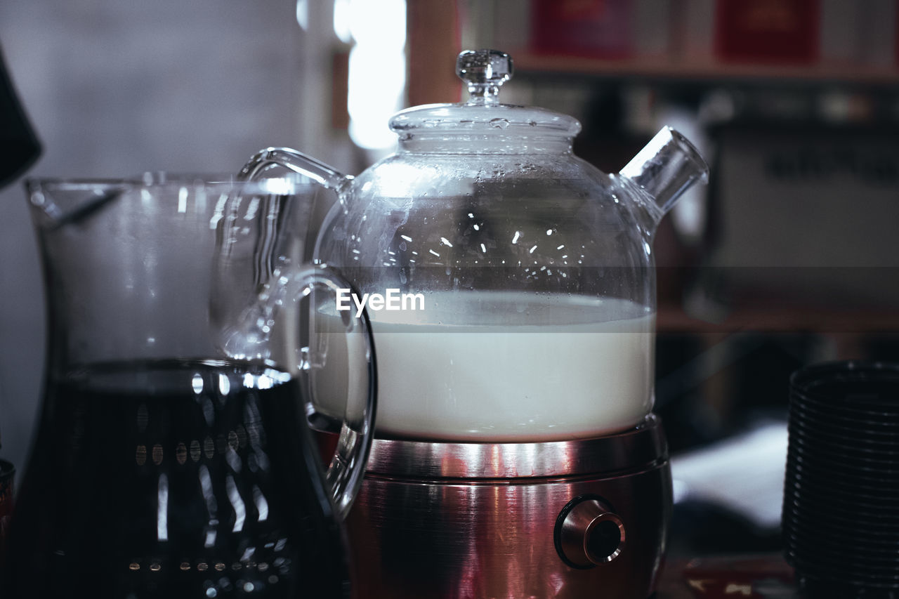 Glass teapot with white steamed milk for making indian masala tea. hot drink.