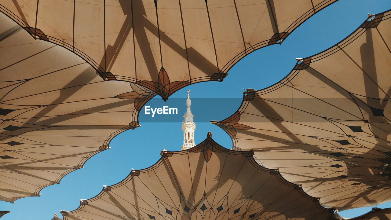 Low angle view of buildings against sky with parasols in foreground