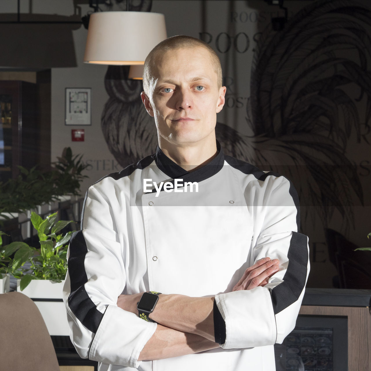 Portrait of confident chef with arms crossed standing at restaurant
