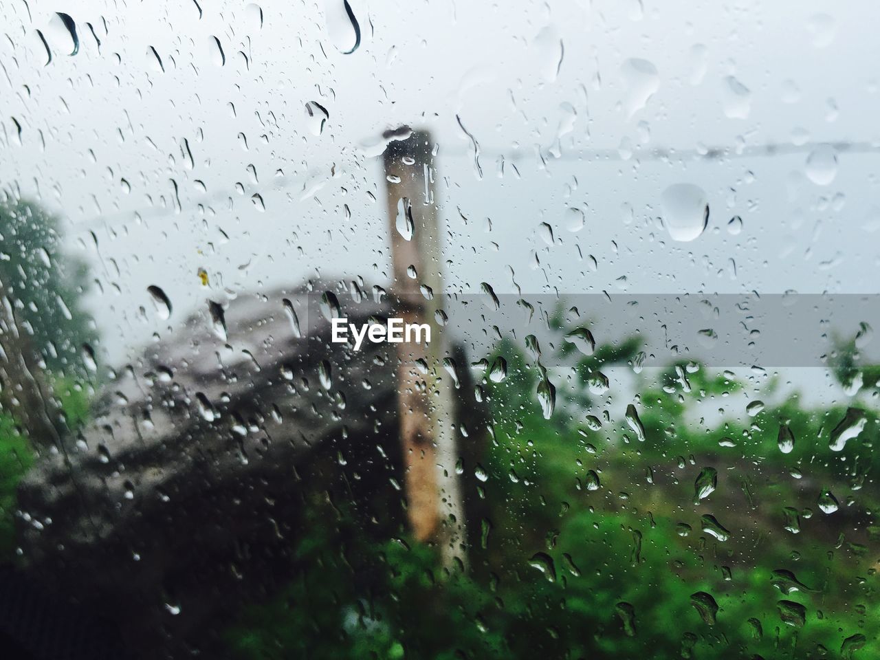 Close-up of wet window against sky during rainy season