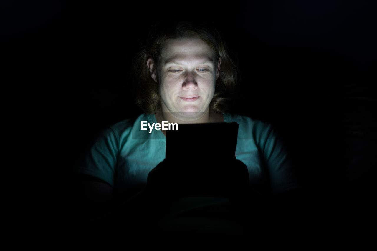 Woman using digital tablet against black background