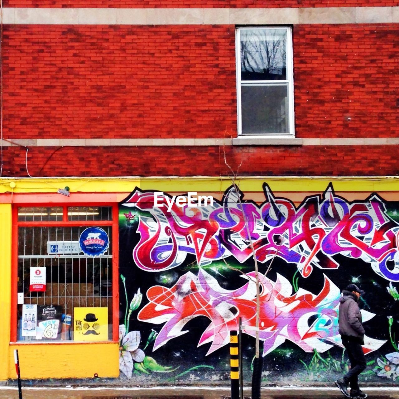 Side view of man walking along graffiti wall