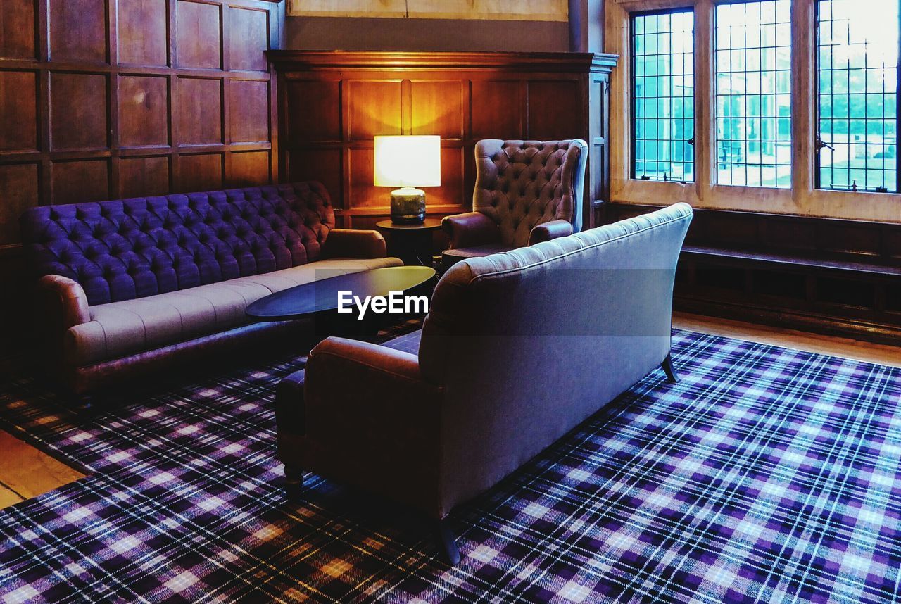 Illuminated electric lamp by sofa on carpet at castle