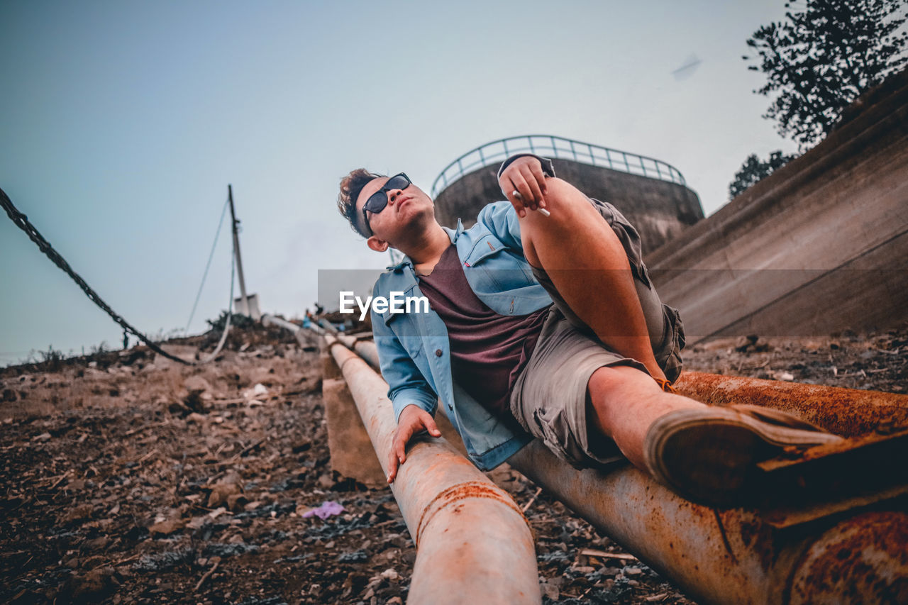 Man sitting on rusty pipe