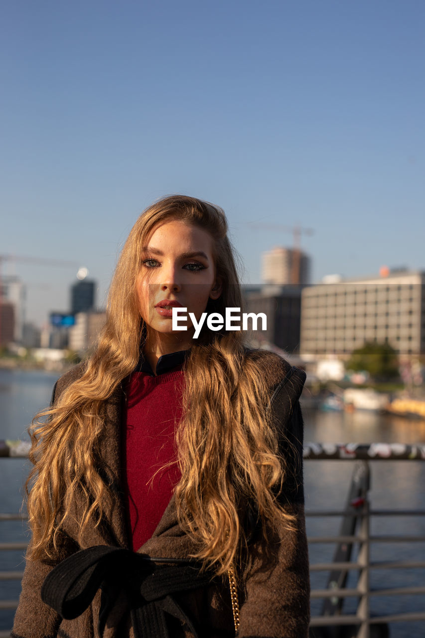 Portrait of young woman standing against sky