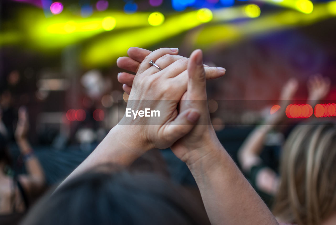 Cropped image of woman with hands clasped at concert