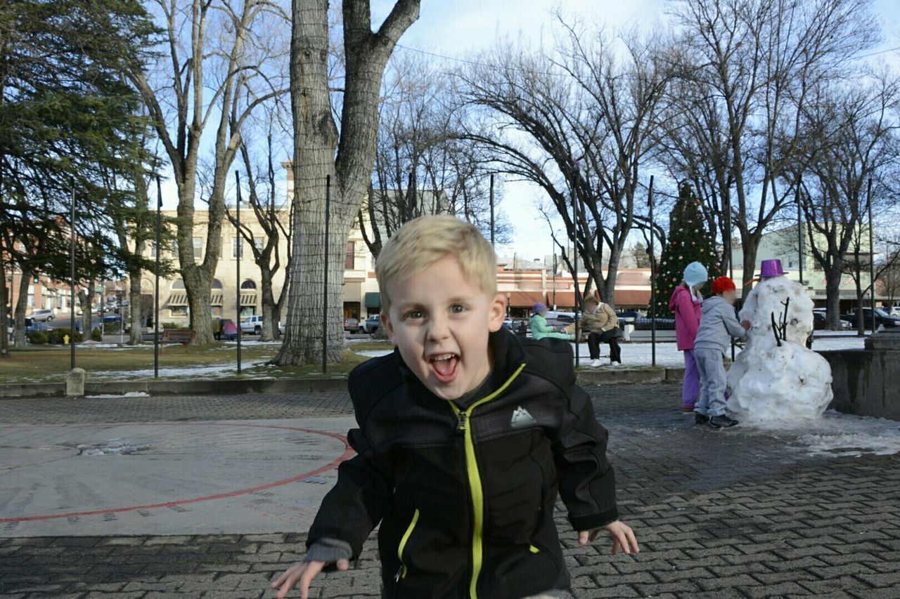 Portrait of cute boy making face in park during winter