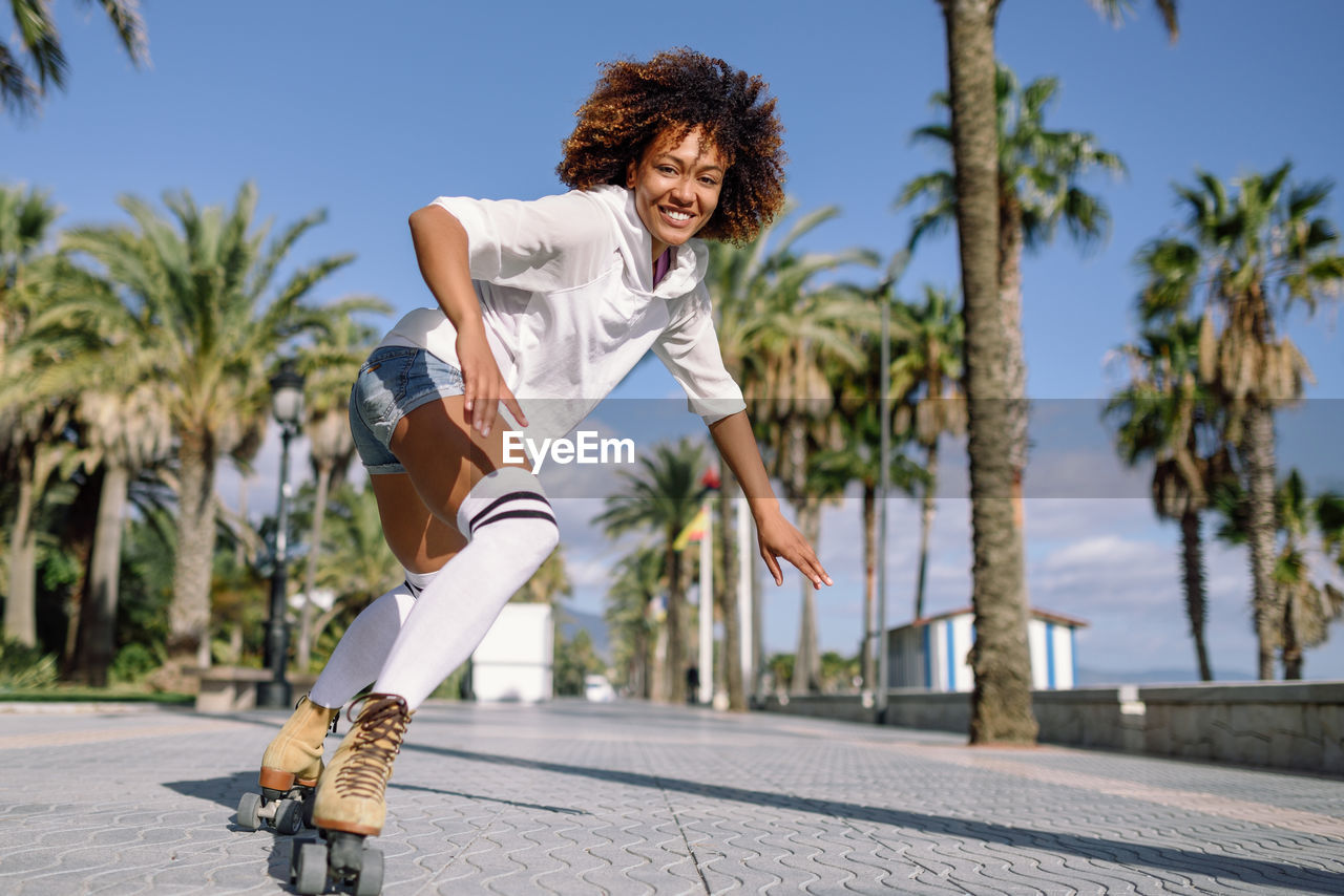 Full length of young woman roller skating on street in city during sunny days