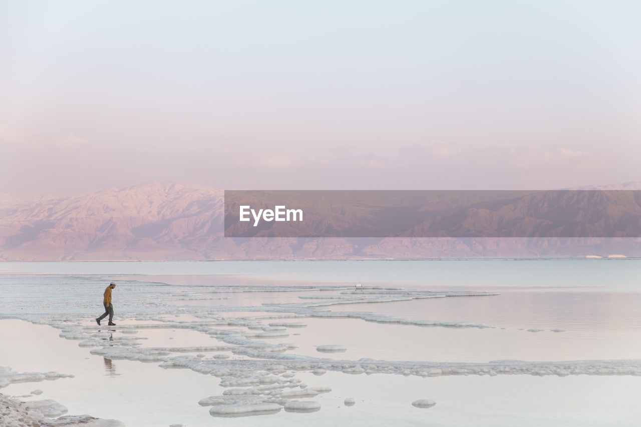 Man walking on salt formations at sunset in dead sea