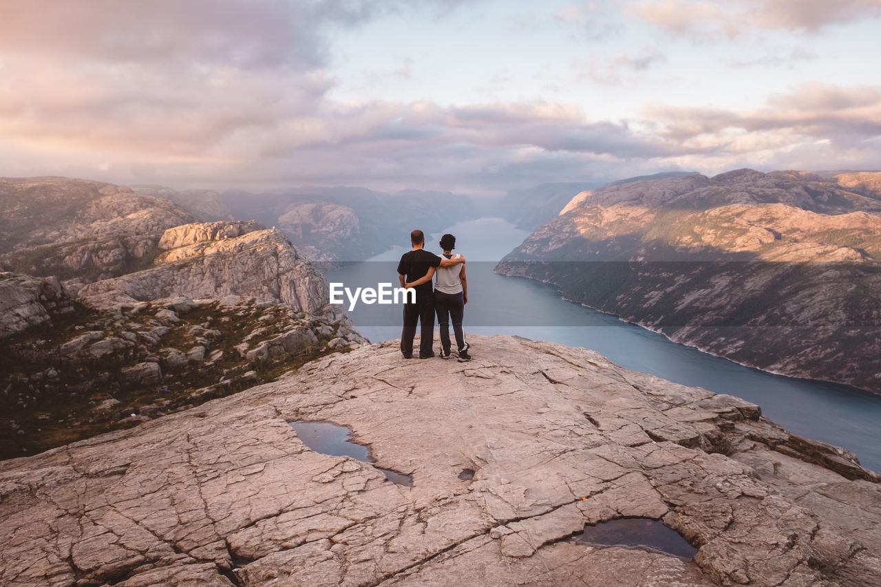 Couple standing at cliff at preikestolen, norway during sunset