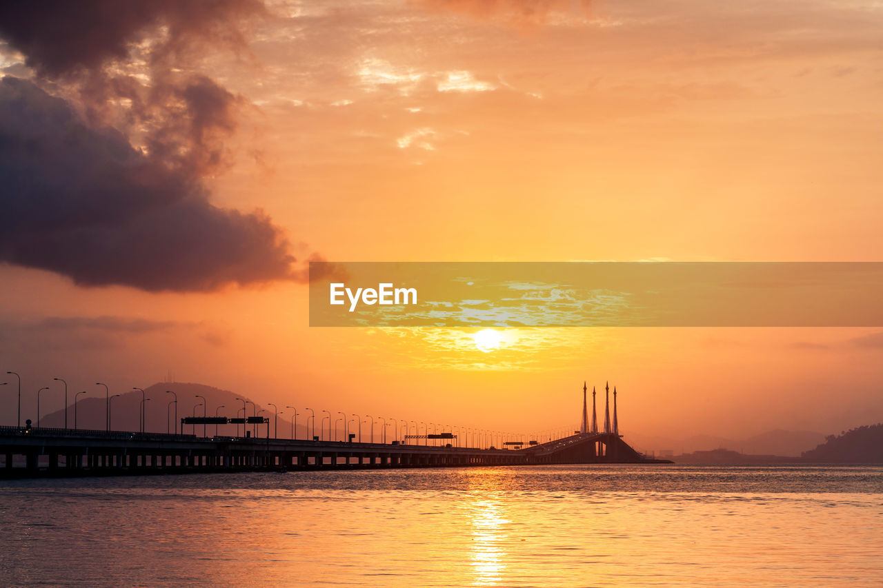 Silhouette of bridge over sea during sunset