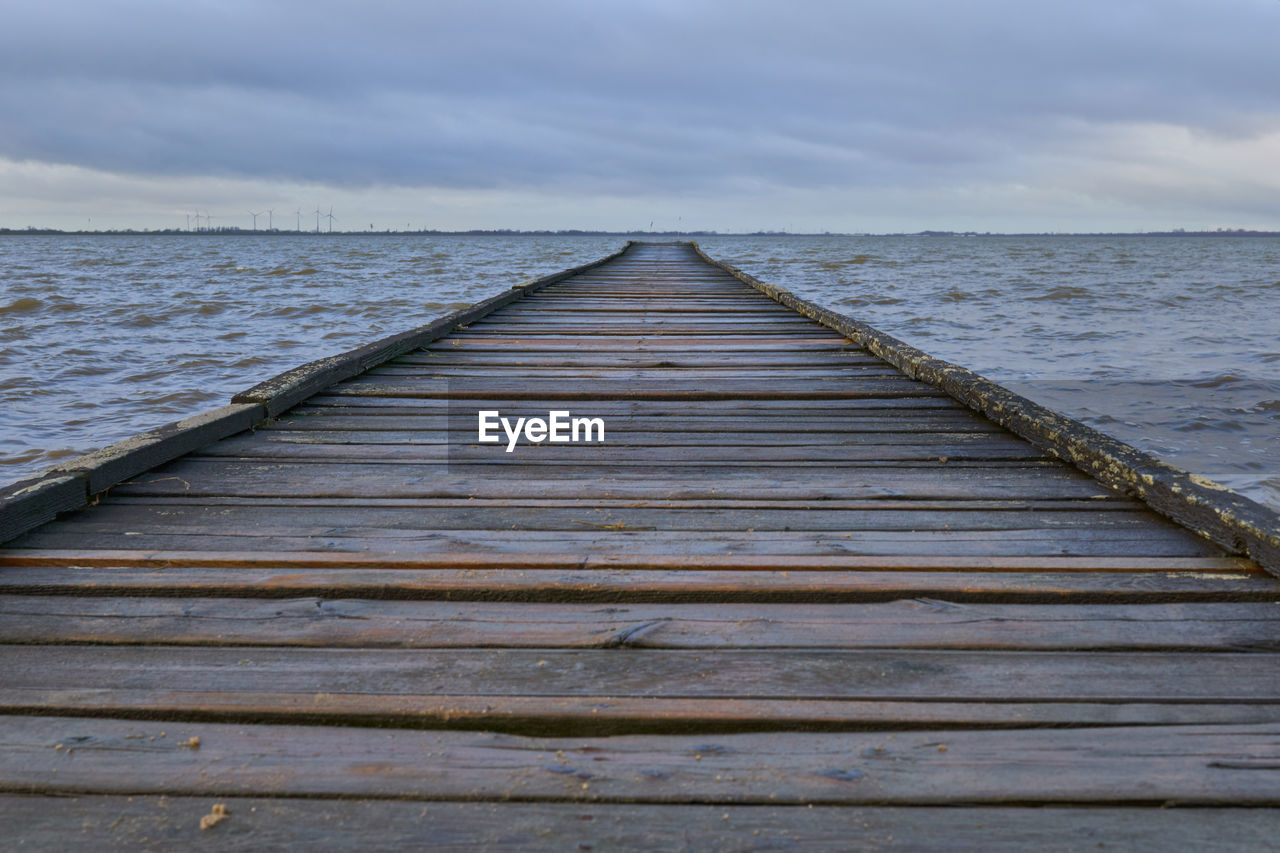 Wooden pier over sea against sky