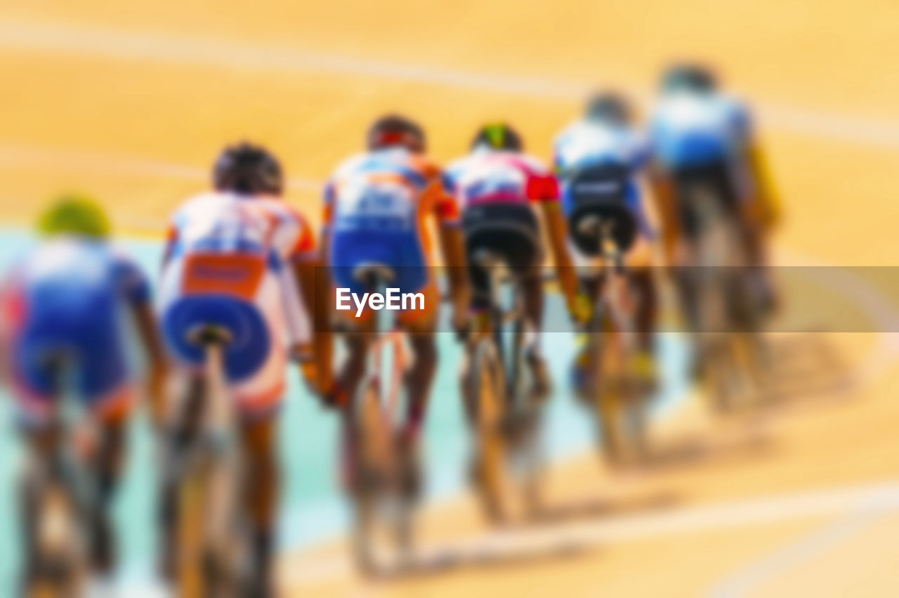 Defocused image of people racing with bicycles on track