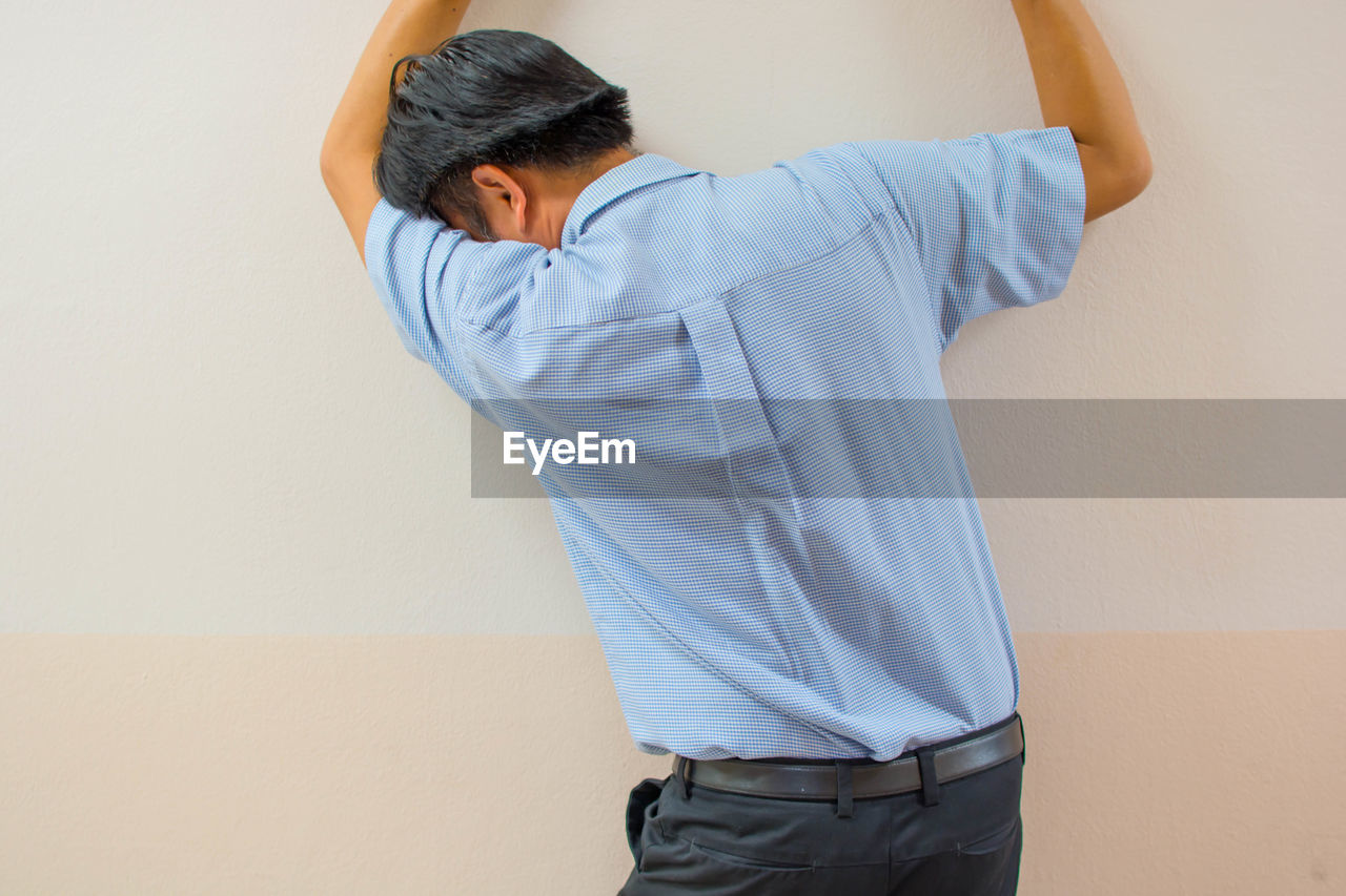 REAR VIEW OF MAN STANDING AGAINST CURTAIN