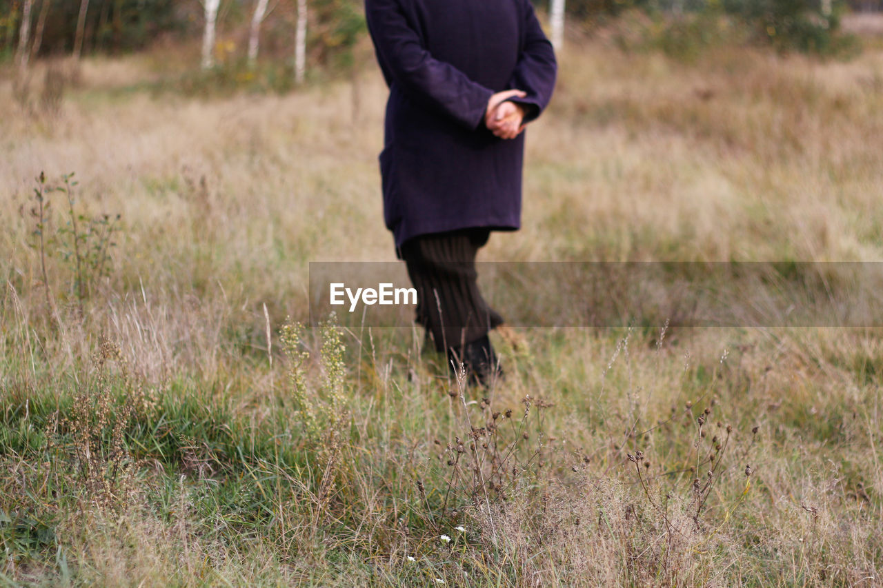 Freedom old woman, female person walking in autumn meadow. fall dry grass. people leaving home, lost