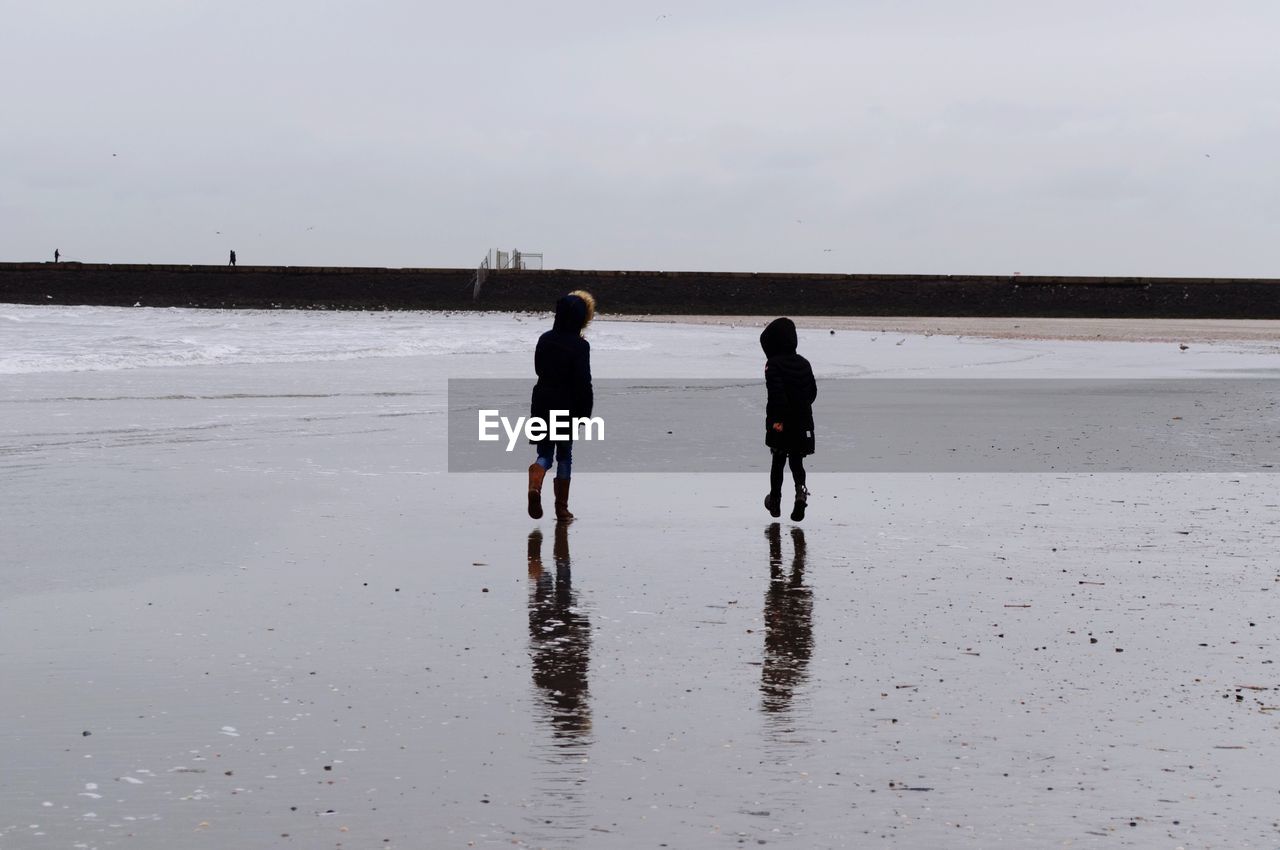 Rear view of siblings walking at beach