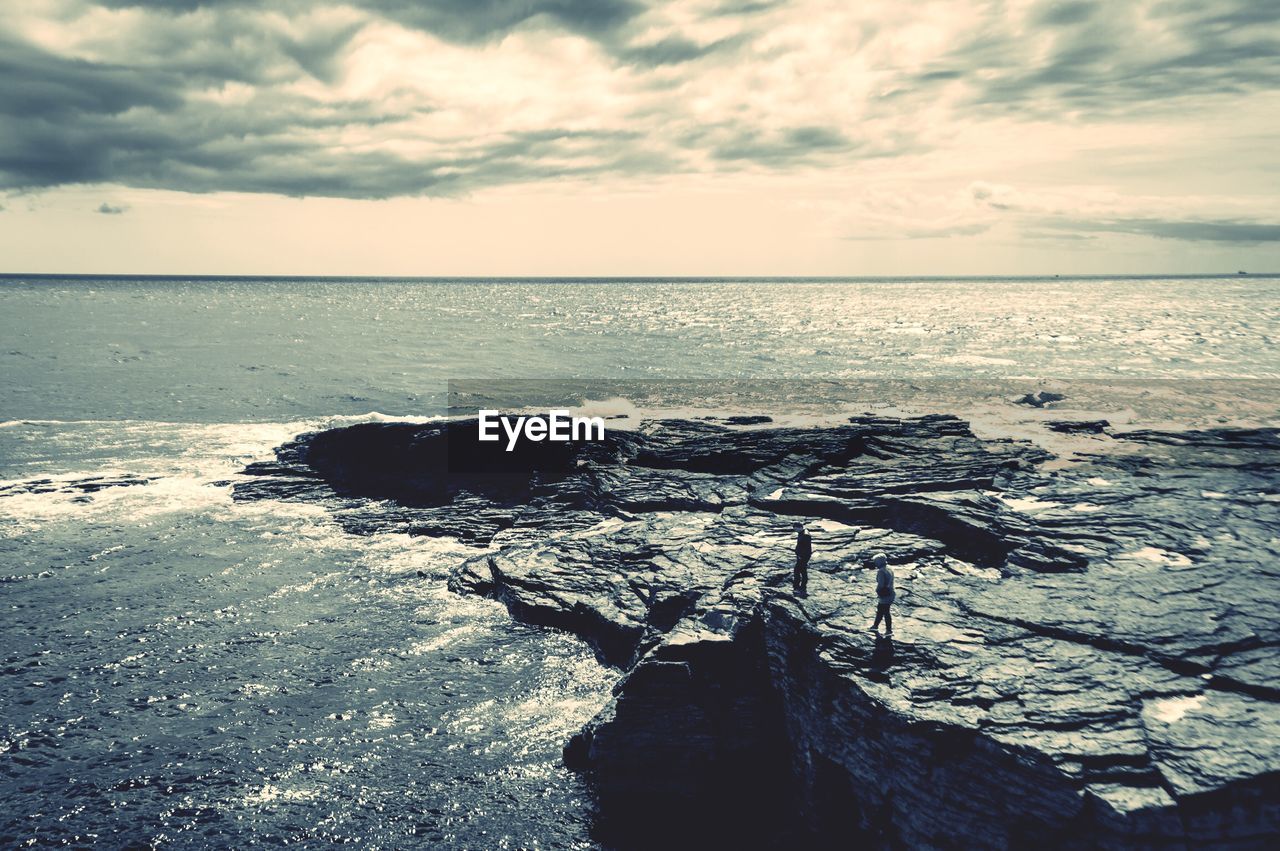 Scenic view of rocky shore and sea against sky