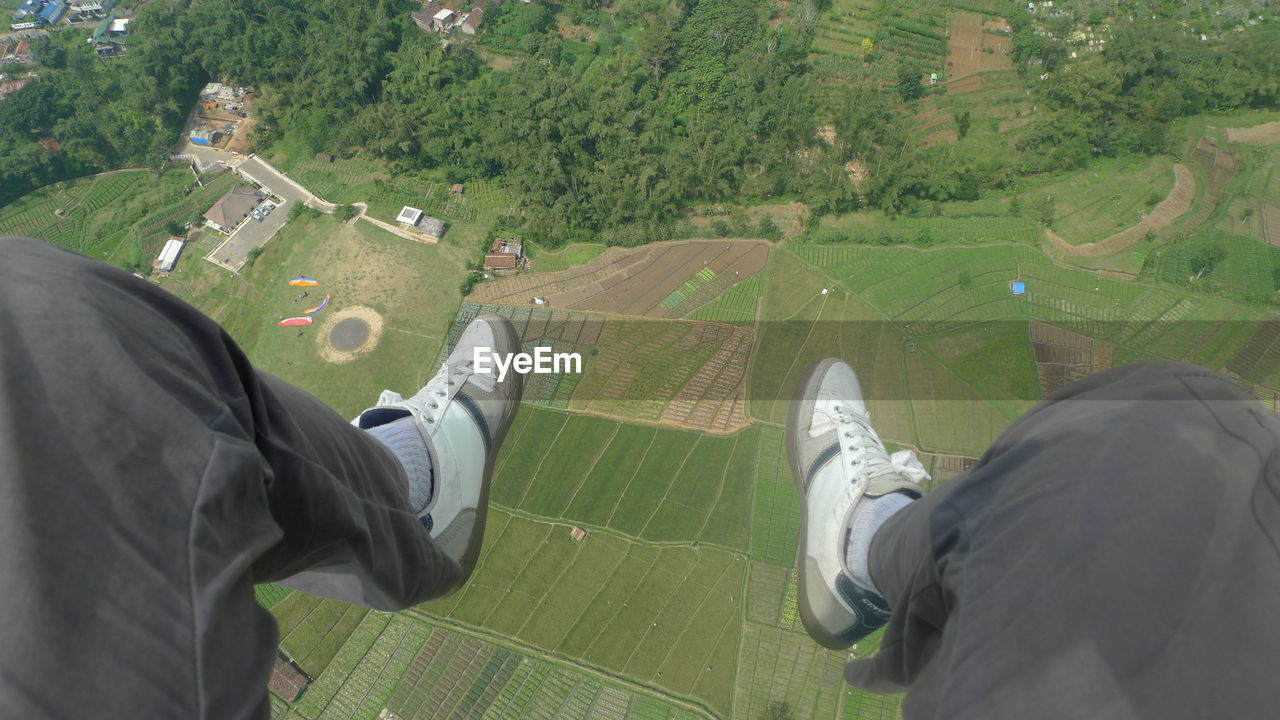 Low section of man paragliding over landscape