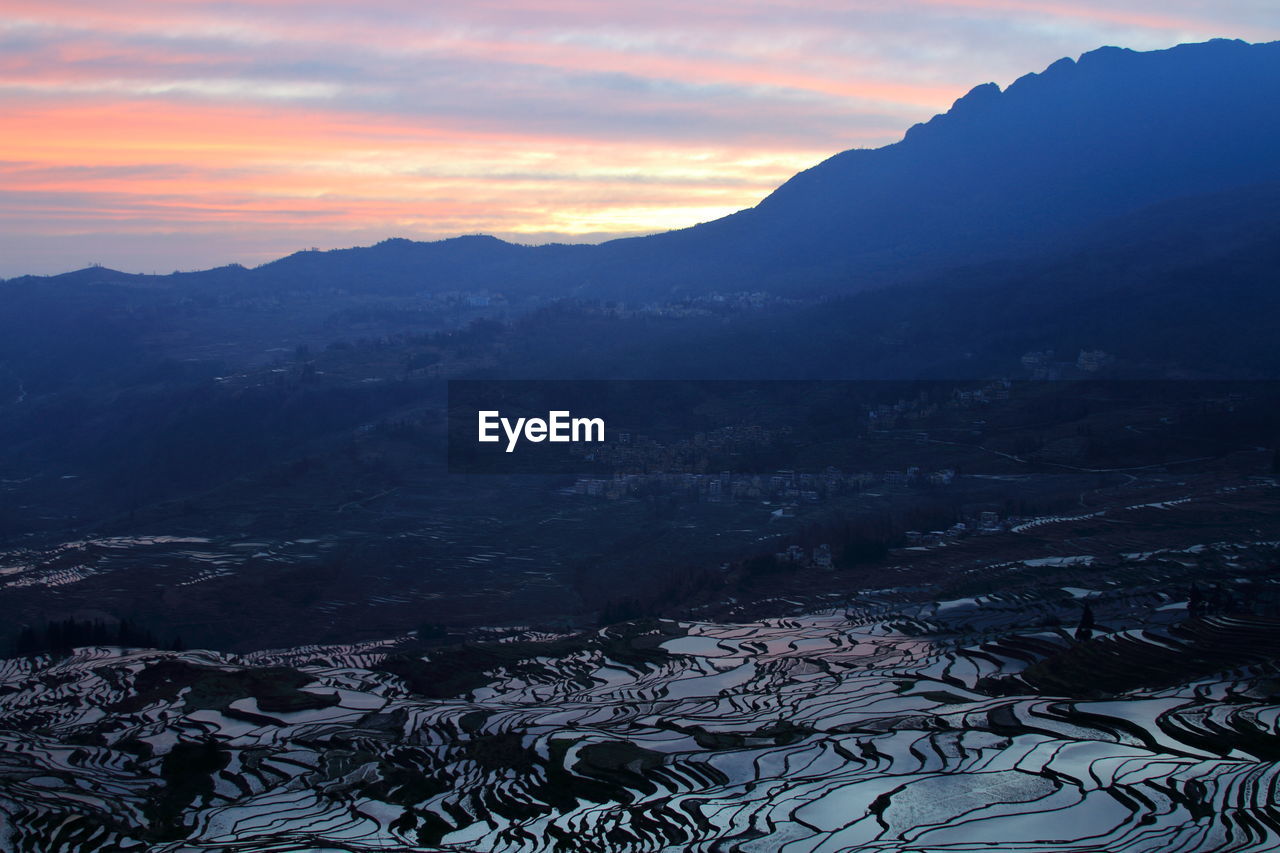 HIGH ANGLE VIEW OF SNOWCAPPED MOUNTAINS AGAINST SKY AT SUNSET