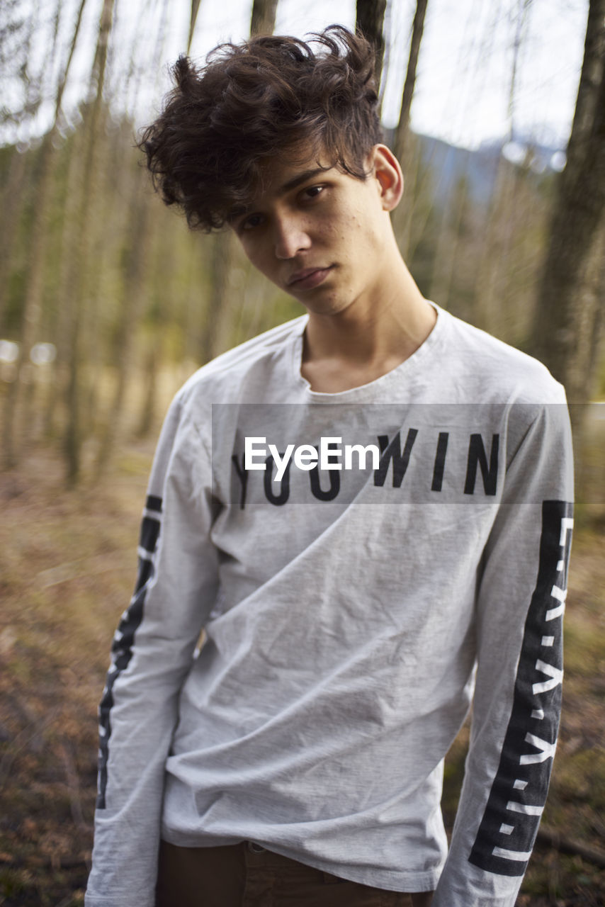 Portrait of young man standing at forest