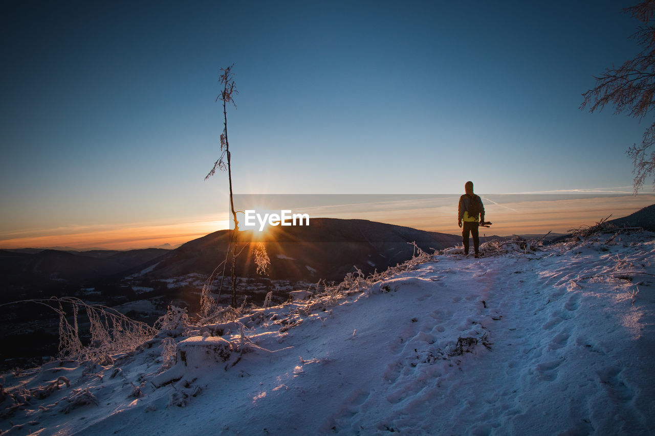 Sunrise in winter in the beskydy mountains in eastern bohemia. a teenager in a colorful jacket
