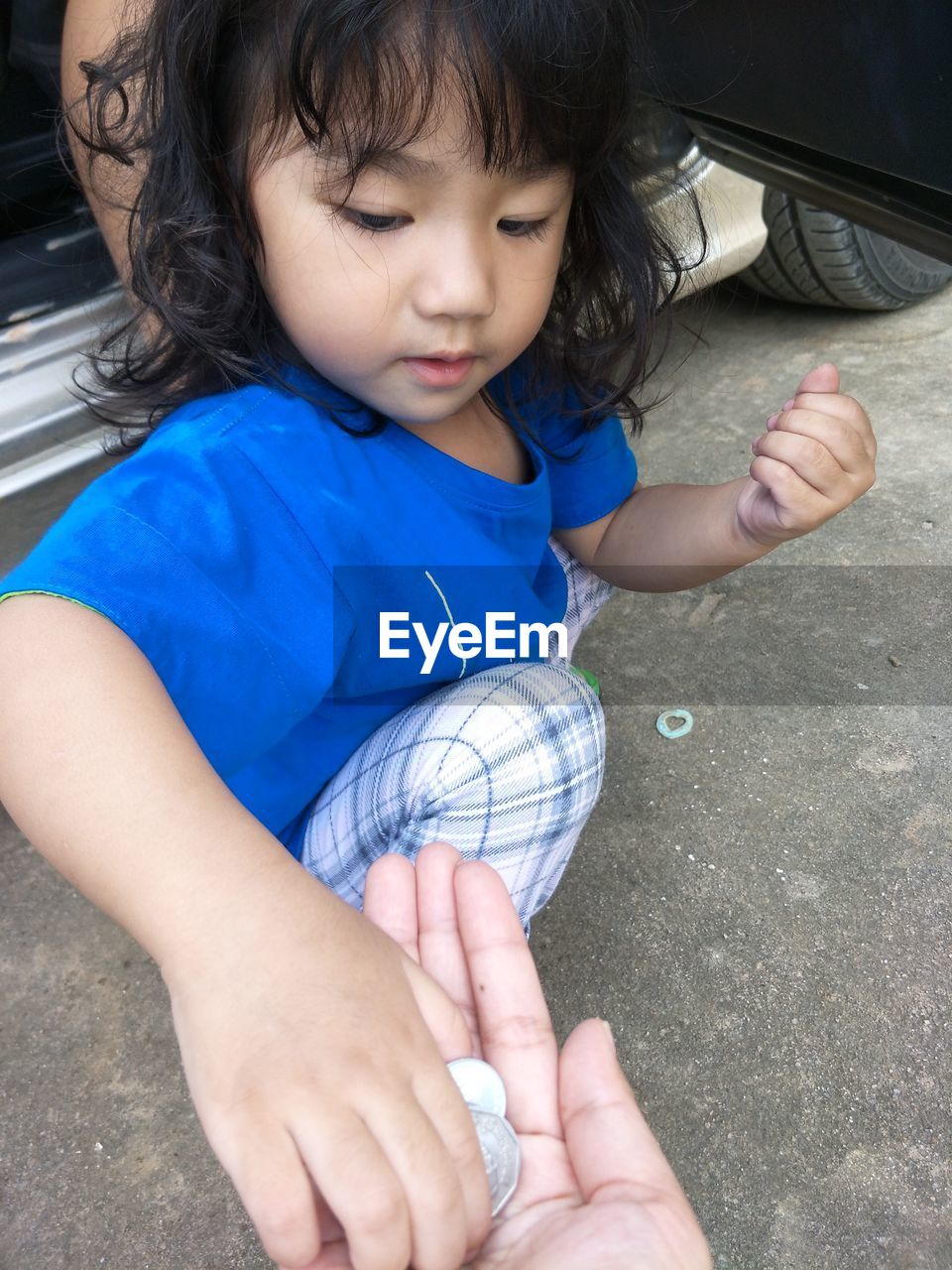 Close-up cropped hand giving coins to girl playing on road