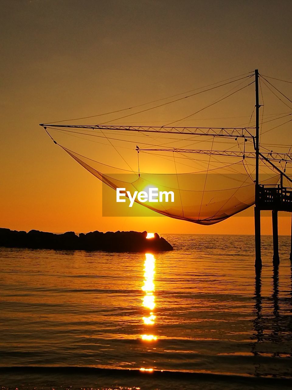 Sunset shining through fishing net over sea