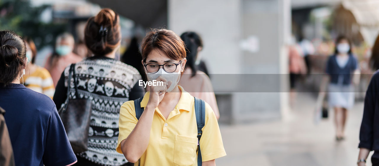 Woman with pollution mask coughing in city