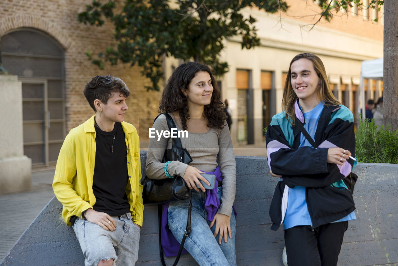 Friends talking while standing outdoors on the street.