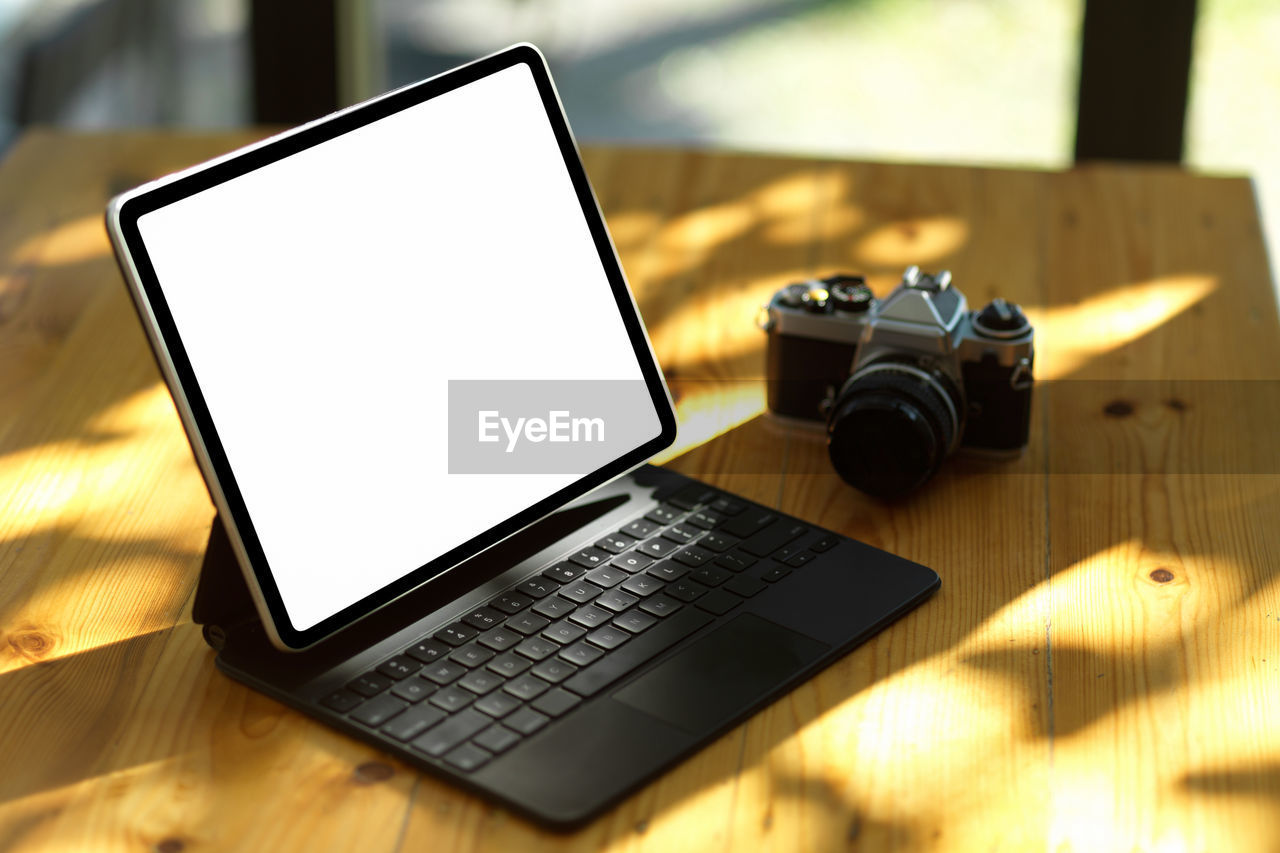 CLOSE-UP OF CAMERA AND LAPTOP ON TABLE