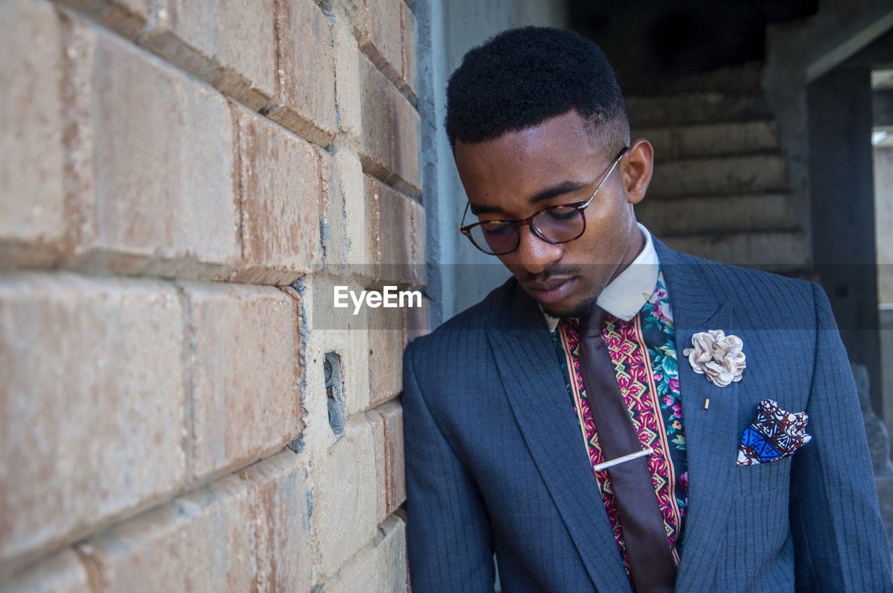 Young man in suit standing against wall