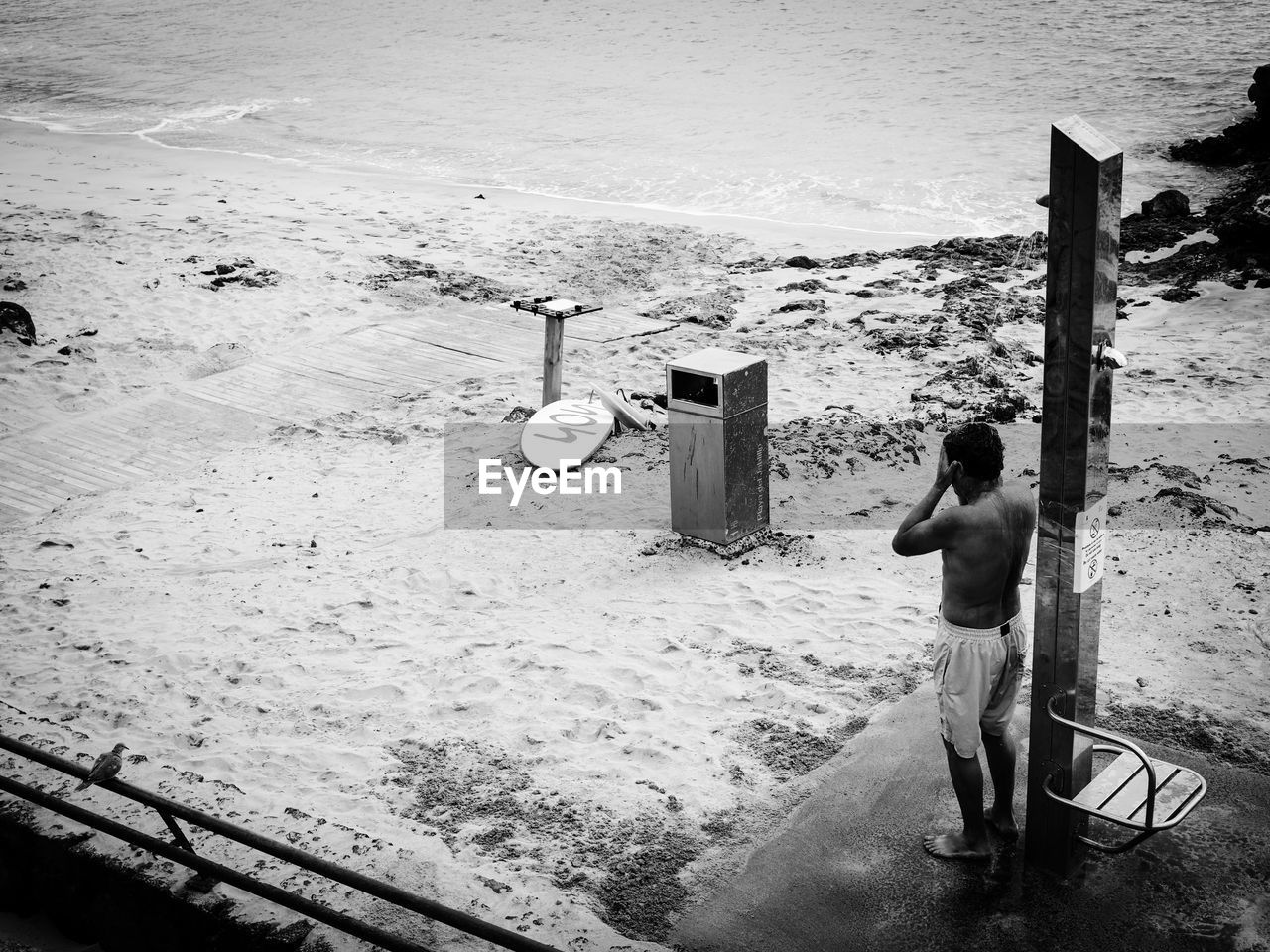 REAR VIEW OF SHIRTLESS WOMAN STANDING ON SHORE