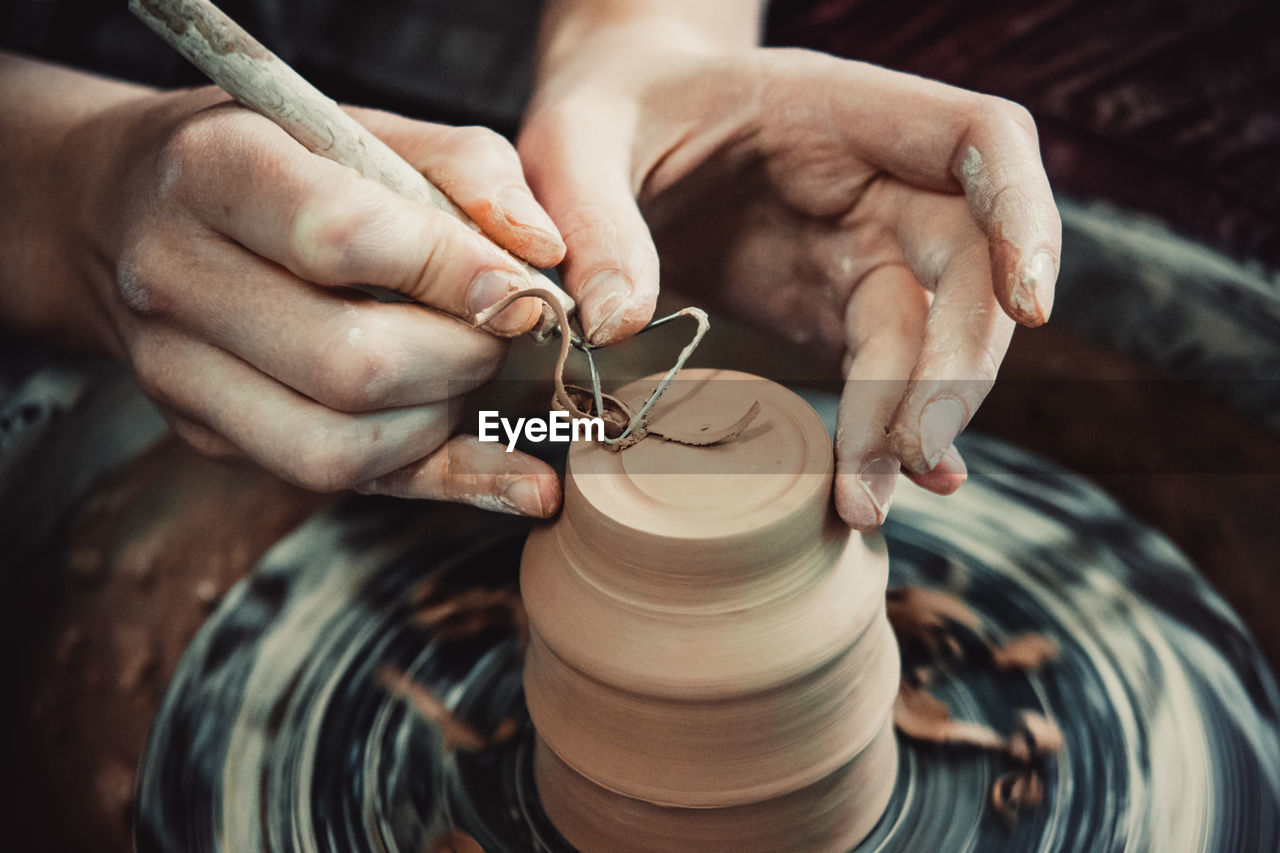 Master removes the top layer of clay on pot with a special tool. create clay vessel. 