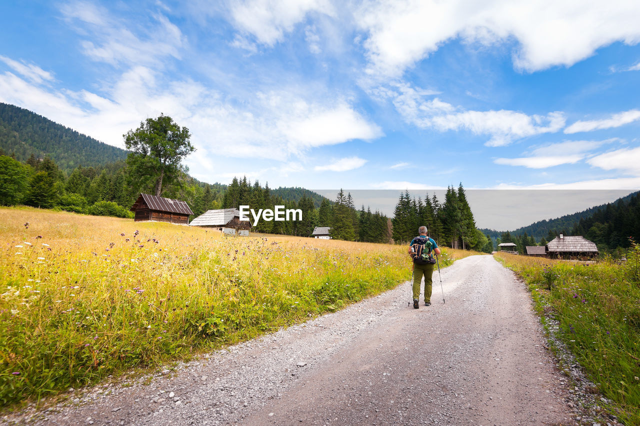 Rear view of man walking on road against sky