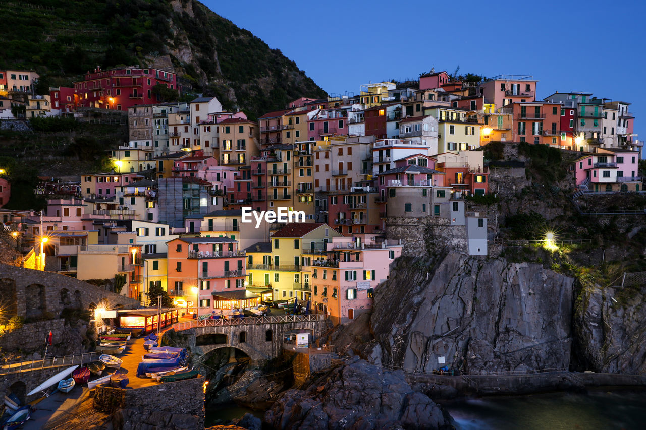 Illuminated manarola at shore against sky during dusk