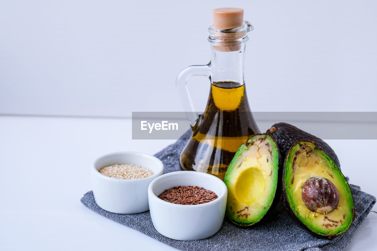 Olive oil in glass bottle with sesame and flax seeds. fresh ripe hass avocado. healthy eating. vegan