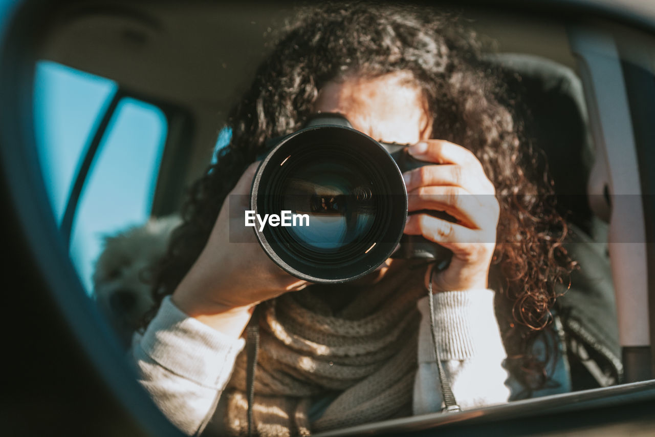 Close-up of woman photographing with camera in car