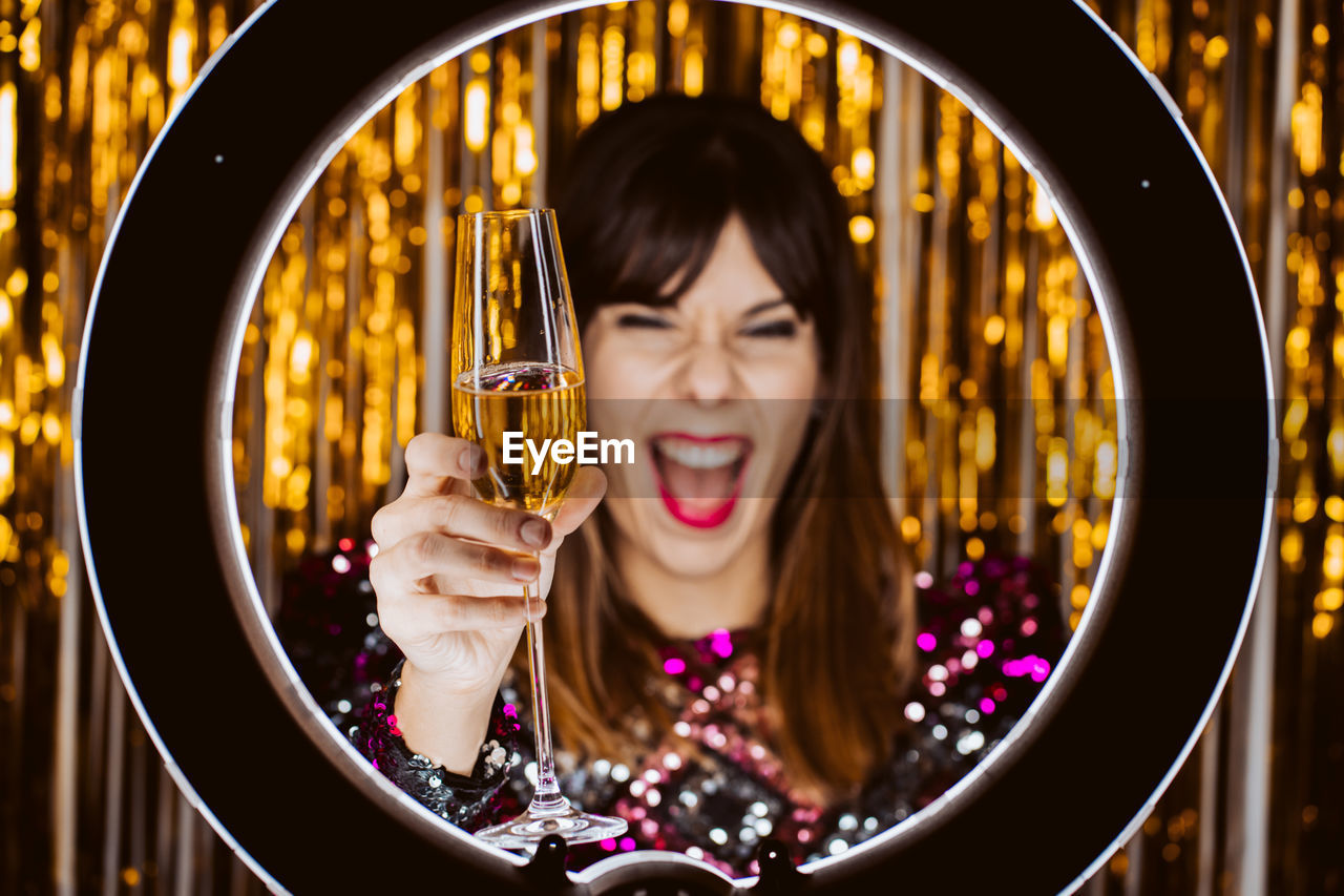 Cheerful young woman with champagne against decorations