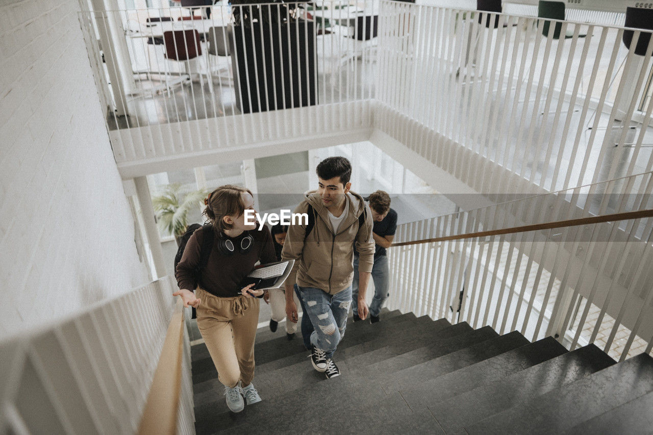 High angle view of students talking while moving up on steps in university