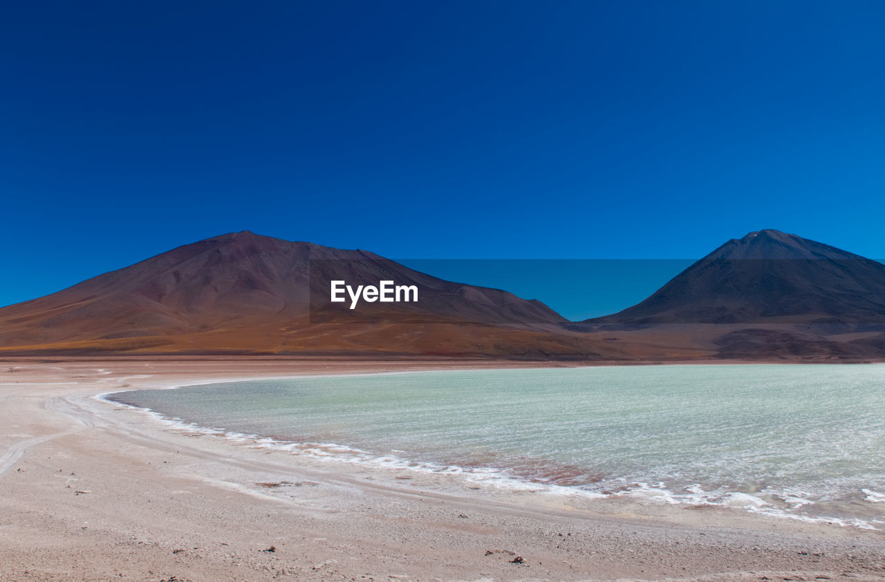 Scenic view of desert against clear blue sky