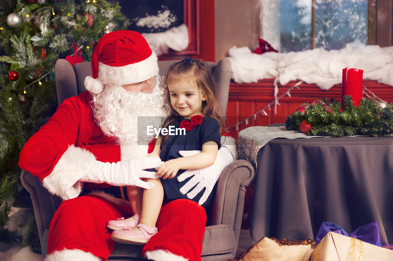 Full length of mother and daughter sitting on christmas tree