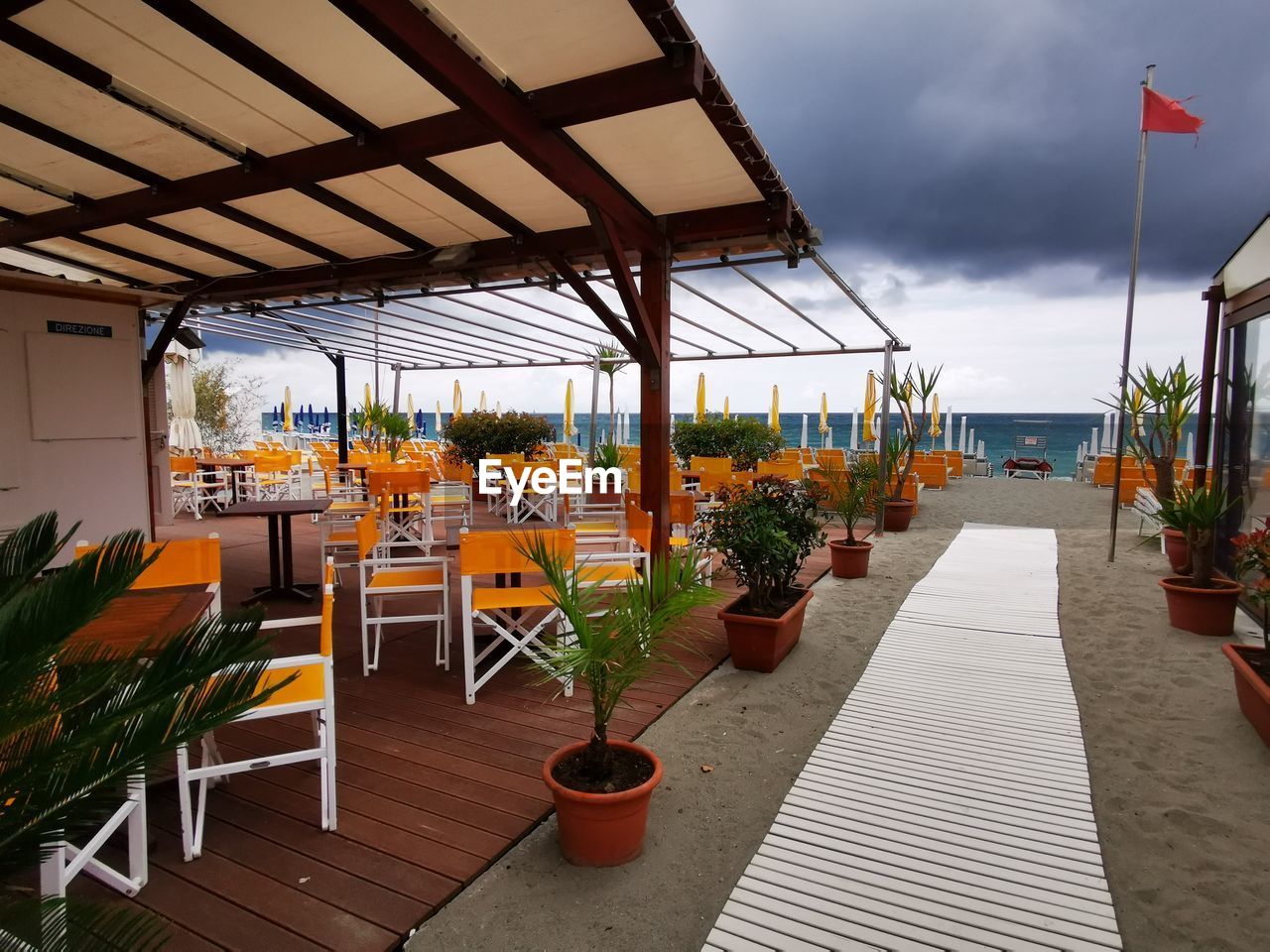 Empty chairs and tables in restaurant against sky