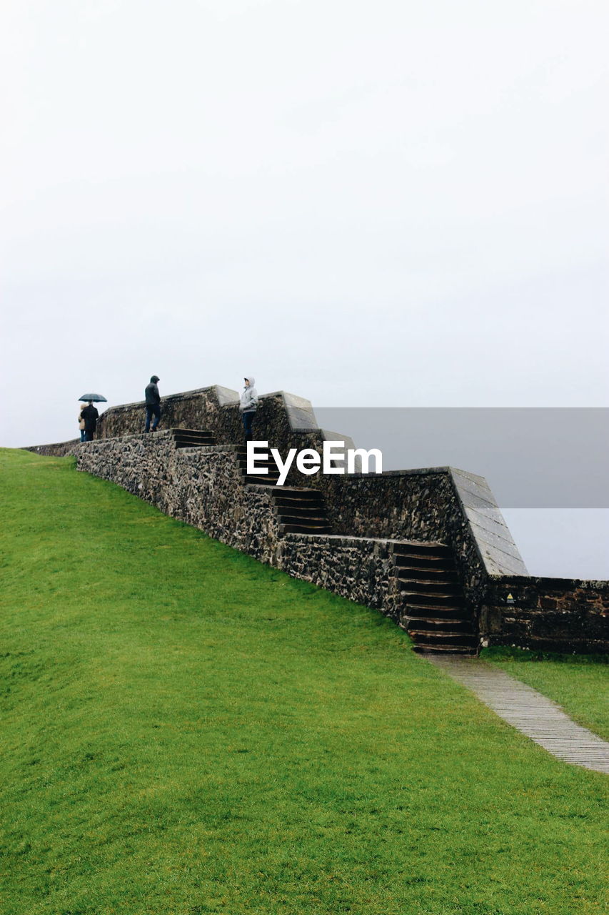 Built structure on grassy hill against clear sky