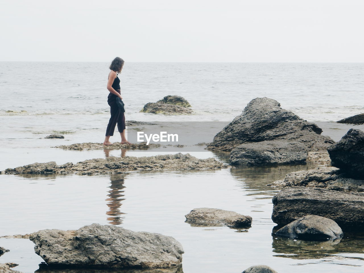 Woman walking on rocks by sea